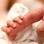 The baby clings to his father’s finger